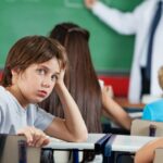Niño que se encuentra en un salón de clases, sin prestar atención a lo que ocurre en el salón, se nota distraído