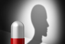 Los fármacos psiquiátricos pueden reducir las capacidades sociales y emocionales Una pastilla, en vertical, la mitad inferior de color rojo, la mitad superior blanca. Refleja una sombra, pero la sombra es la silueta de perfil de una persona.