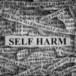 Tiras de papel rasgadas con la inscripción "Self Harm" que en español se traduciría como "Daño Autoinflingido"