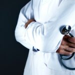 imagen de un médico con bata blanca y estetoscopio en mano, cruzando los brazos